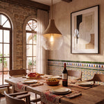 Lámpara de diseño colgante con pantalla de vidrio texturizado sobre mesa de comedor rústica.
