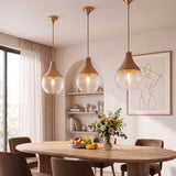 Tres lámparas de techo colgantes de cristal y madera sobre una mesa de comedor moderna