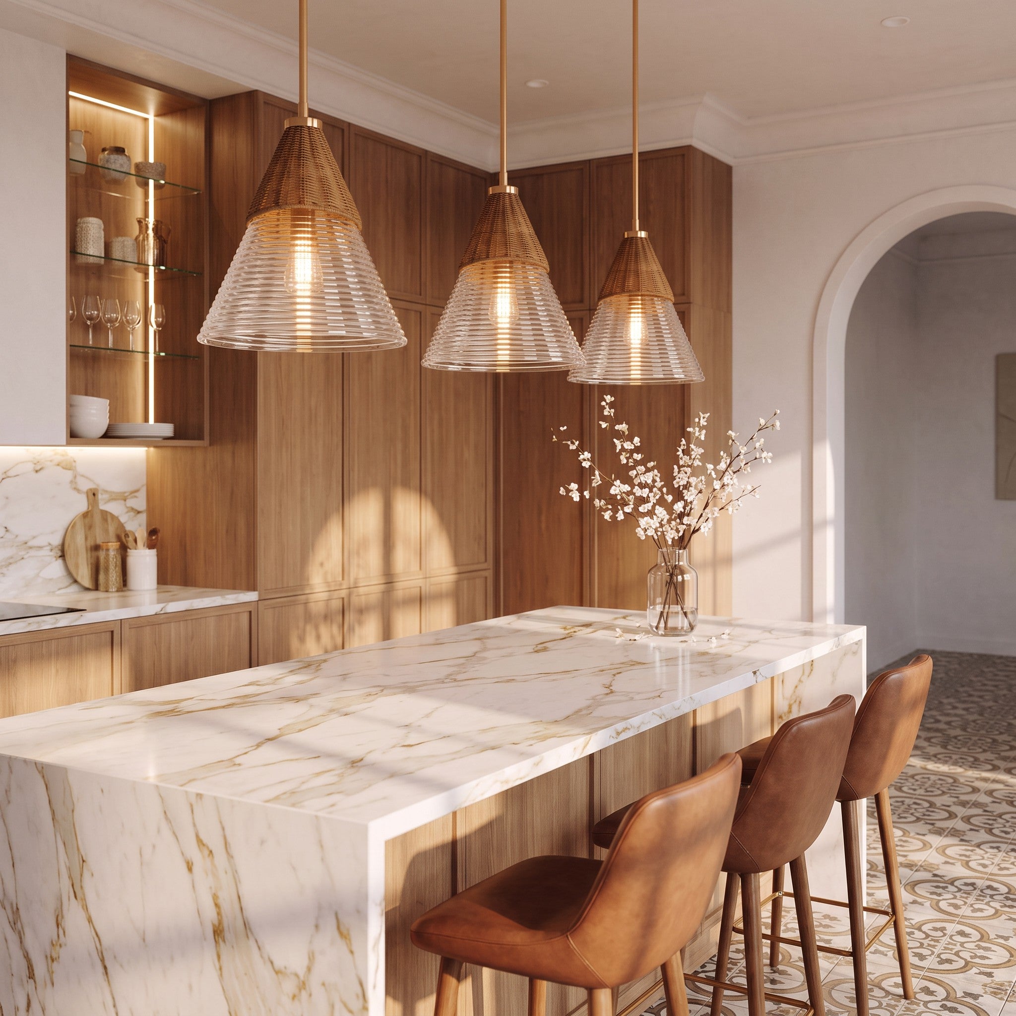 Tres lámparas de diseño colgantes sobre una isla de cocina de mármol blanco.